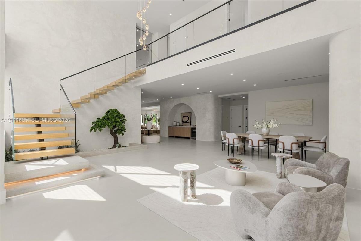 Open-concept interior featuring a floating staircase with wood treads and glass railings, polished concrete flooring, a custom arched wall niche, and 