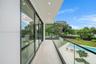 Covered balcony featuring expansive sliding glass doors, frameless glass railings, recessed lighting, and tile flooring