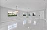 Polished stone-finish flooring, multi-pane windows with black frames, and a tiered crystal chandelier