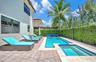 Rear patio featuring a swimming pool with integrated spa, paver hardscaping, and privacy hedges