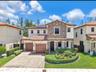 Two-story exterior featuring a stone facade, tile roof, dual-car garage, solar panels, and a paved driveway