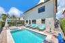 In-ground pool with integrated spa, stone-paver pool deck, and wood-framed pergola
