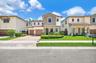 Two-story residence featuring a stone-veneer façade, clay tile roof, dual-car garage, and a manicured front lawn
