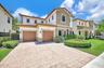 Two-story residence featuring a stone veneer facade, paver driveway, two-car garage, and manicured landscaping