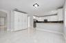 Kitchen featuring white shaker-style cabinetry, a stone-patterned breakfast bar, stainless steel appliances, and large-format porcelain tile flooring