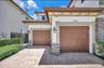 Stucco exterior with stone veneer accents, dual-car garage with paneled doors, and paved driveway