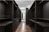 Custom walk-in storage featuring dark-finish cabinetry, built-in shelving, integrated pull-out drawers, metal garment rods, and wood-finish flooring