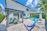 Outdoor living space featuring a paved stone patio, covered pergola, in-ground swimming pool, integrated spa, and perimeter privacy hedges