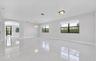 Open-concept interior featuring large-format polished tile flooring, black-framed windows, a multi-light chandelier, and an arched entryway