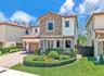 Two-story residence featuring a tile roof, decorative stone veneer façade, manicured landscaping, and a paved driveway