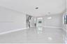 Open-concept interior featuring large-format polished stone-finish flooring, a curved staircase with a dark wood handrail, an arched entryway, and a t