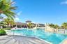Swimming pool with stone-clad bridge, tiered entry steps, metal handrails, and paver decking