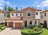 Stucco and multi-textured stone exterior featuring a tile roof, solar panels, paver driveway, and professional landscaping
