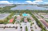 Aerial perspective of the community center featuring a swimming pool, tennis court, basketball court, and central fountain, situated alongside a lake