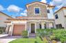 Two-story exterior featuring stone veneer accents, a tiled roof, a paved driveway, and an arched entry with recessed lighting