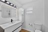 Bathroom featuring a floating vanity with a integrated basin, matte black faucet, wall-mounted storage cabinet, and large rectangular mirror with peri