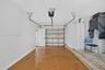 Single-car garage featuring a roll-up door, automated door opener, built-in storage cabinetry, and concrete flooring