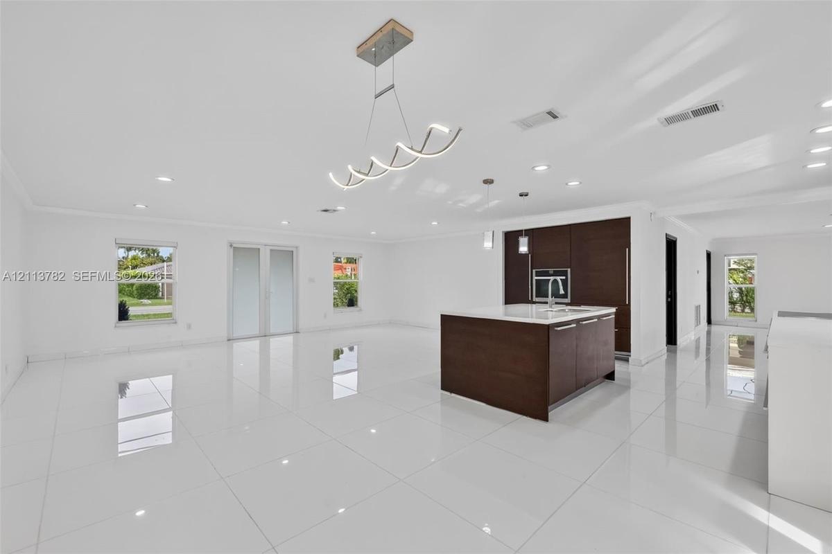 Open-concept interior featuring large-format tile flooring, a center island with a stone countertop, dark wood-finish cabinetry, recessed lighting, an