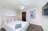 Room featuring wood-finish flooring, a white ceiling fan with integrated lighting, and dark-finish closet doors