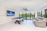 Spacious interior featuring high-gloss tile flooring, recessed ceiling lighting, a brushed-nickel ceiling fan, and extensive floor-to-ceiling glass sl