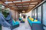 Covered patio featuring a timber-frame pergola, natural stone flooring, slatted wood privacy screen, and recessed pendant lighting
