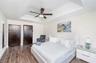 Tray ceiling featuring a central multi-blade ceiling fan, dark-finish doors, and wood-finish flooring