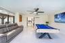 Polished tile flooring, wall-mounted ductless air conditioning unit, ceiling fan with integrated lighting, and floor-to-ceiling glass sliding doors