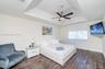 Tray ceiling featuring a central five-blade brushed-nickel ceiling fan with integrated lighting and dark wood-finish flooring