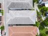 Aerial perspective of a multi-structure property featuring neutral-toned tile roofing, paved pedestrian pathways, and manicured perimeter landscaping 