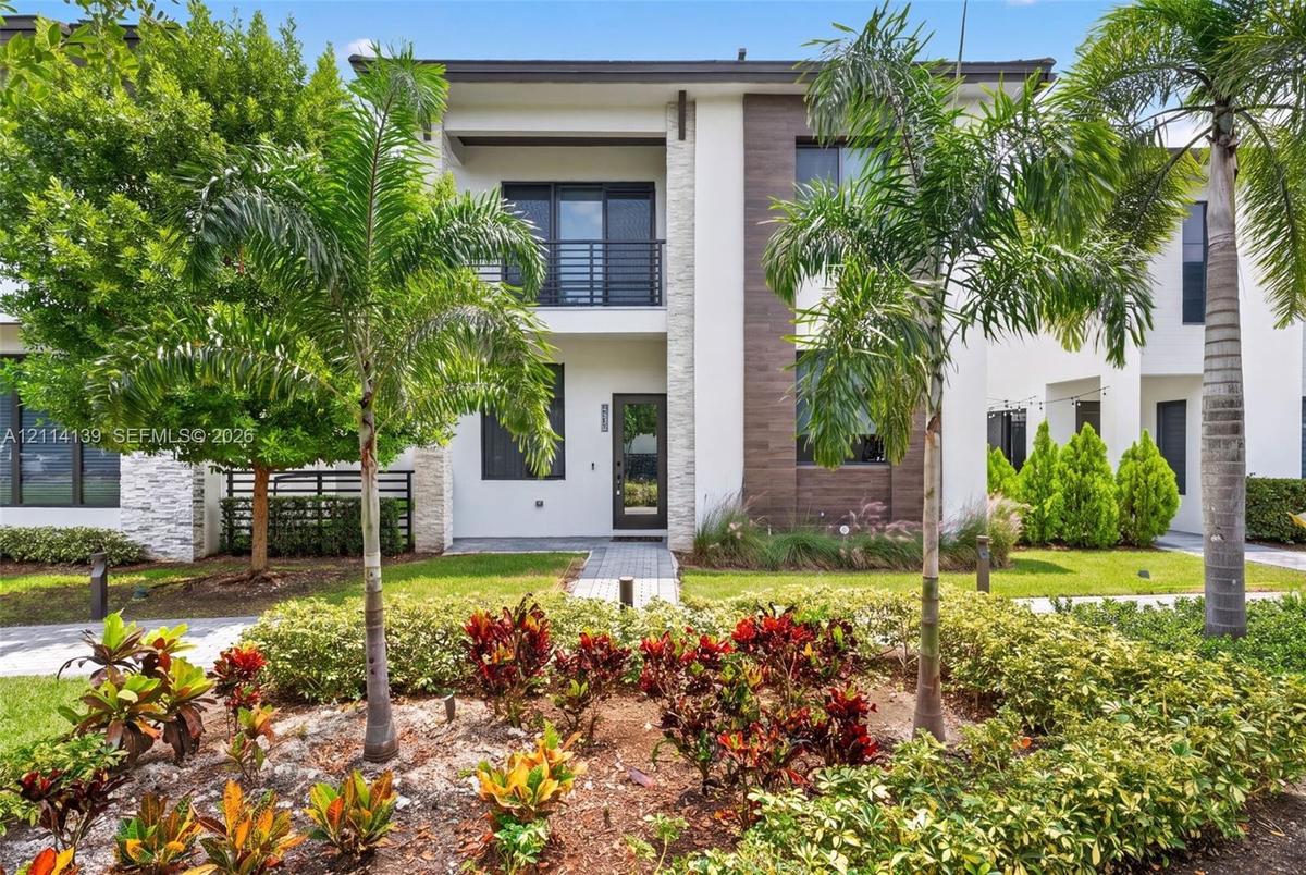 Modern two-story exterior featuring a white stucco facade, stacked stone accents, wood-finish siding, and a balcony with horizontal metal railings