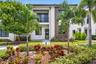 Modern two-story exterior featuring a white stucco facade, stacked stone accents, wood-finish siding, and a balcony with horizontal metal railings