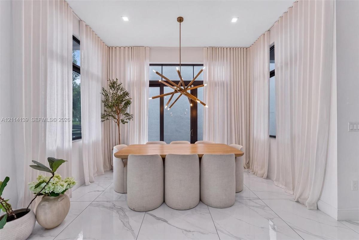 Large-format stone tile flooring, floor-to-ceiling drapery, multi-paned windows, and a multi-arm metallic chandelier