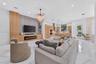 Large-format tile flooring, custom light-toned cabinetry, integrated fireplace, expansive stone-finish feature wall, and recessed ceiling lighting