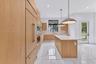 Kitchen featuring flat-panel wood-finish cabinetry, a center island with a stone-surface countertop, built-in panel-ready refrigeration, large-format 
