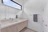 Floating vanity featuring light-toned cabinetry, dual rectangular undermount sinks, stone-finish countertops, and an expansive wall-to-wall mirror pos
