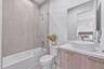 Bathroom featuring a wood-finish vanity with a stone-composite countertop, oval vessel sink, glass shower screen, and wall-to-wall mirror