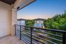 Covered balcony featuring stone-clad pillar, metal railing, and tile flooring