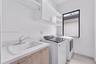 Utility space featuring a drop-in sink, stone-composite countertop, light-finish cabinetry, white upper storage cabinets, and tile flooring