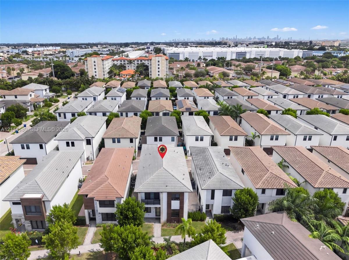 Aerial perspective featuring a two-story residence with a multi-hipped roofline, stucco exterior, and a built-in balcony