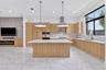 Modern kitchen featuring light-tone wood cabinetry, a center island with a stone countertop, large-format tile flooring, recessed lighting, and two pe