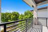 Covered balcony featuring matte black horizontal railings, stone-veneer column, and tile flooring