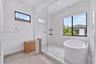 Walk-in glass-enclosed shower featuring stone-finish wall tile, a mosaic tile shower floor, built-in shelving, and an integrated soaking tub
