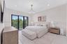 Spacious room featuring light-toned flooring, recessed lighting, a modern metal-finish pendant light, and black-framed sliding glass doors opening to 