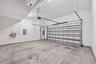 Multi-car garage featuring a concrete floor, sectional roll-up door, automated garage door opener, and integrated overhead lighting