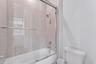 Full-height ceramic tile shower surround with a built-in recessed window, polished chrome shower fixtures, sliding glass shower door, and an acrylic b
