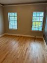 Room featuring wood-finish flooring, dual windows with fitted blinds, and crown molding