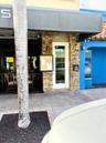 Exterior facade featuring stone veneer detailing, a full-length glass pane entrance door, a metal awning, and wall-mounted exterior lighting