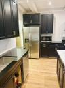 Kitchen featuring shaker-style cabinetry with gold-toned hardware, stainless steel appliances, dark stone-finish countertops, wood-finish flooring, an