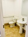 Bathroom featuring wainscoting, a pedestal sink with a single-handle faucet, stone-finish floor tiling, and a wall-mounted grab bar