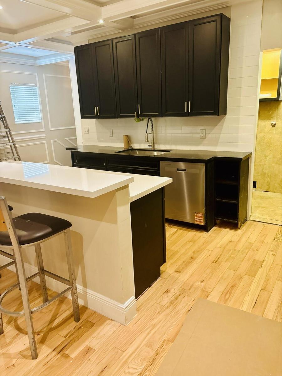 Kitchen featuring custom dark-toned cabinetry, quartz countertops, stainless steel undermount sink with goose-neck faucet, integrated dishwasher, and 
